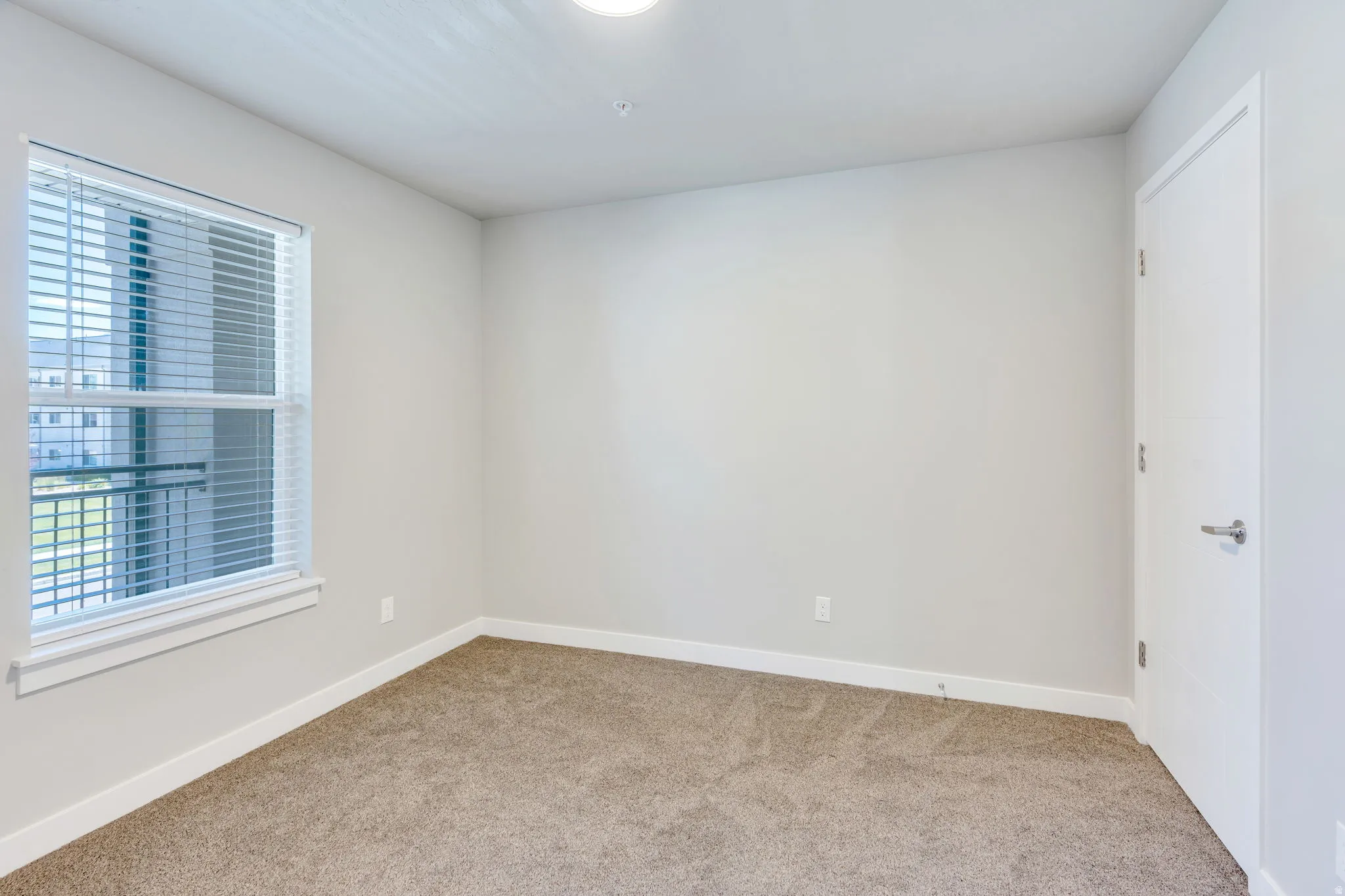 Room featuring carpet flooring, light neutral-toned walls, and a window with blinds