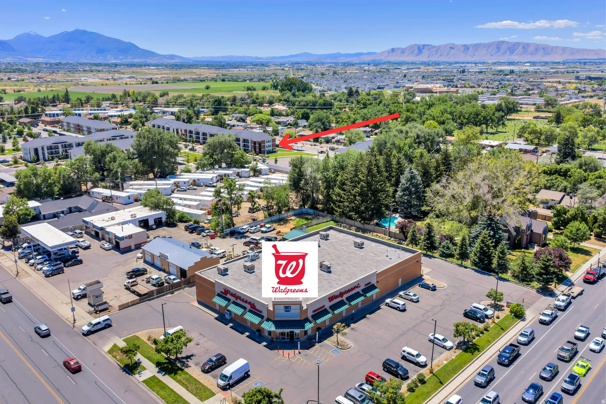 Aerial perspective showcasing a commercial property with a large parking area, green awning features, and clear street frontage