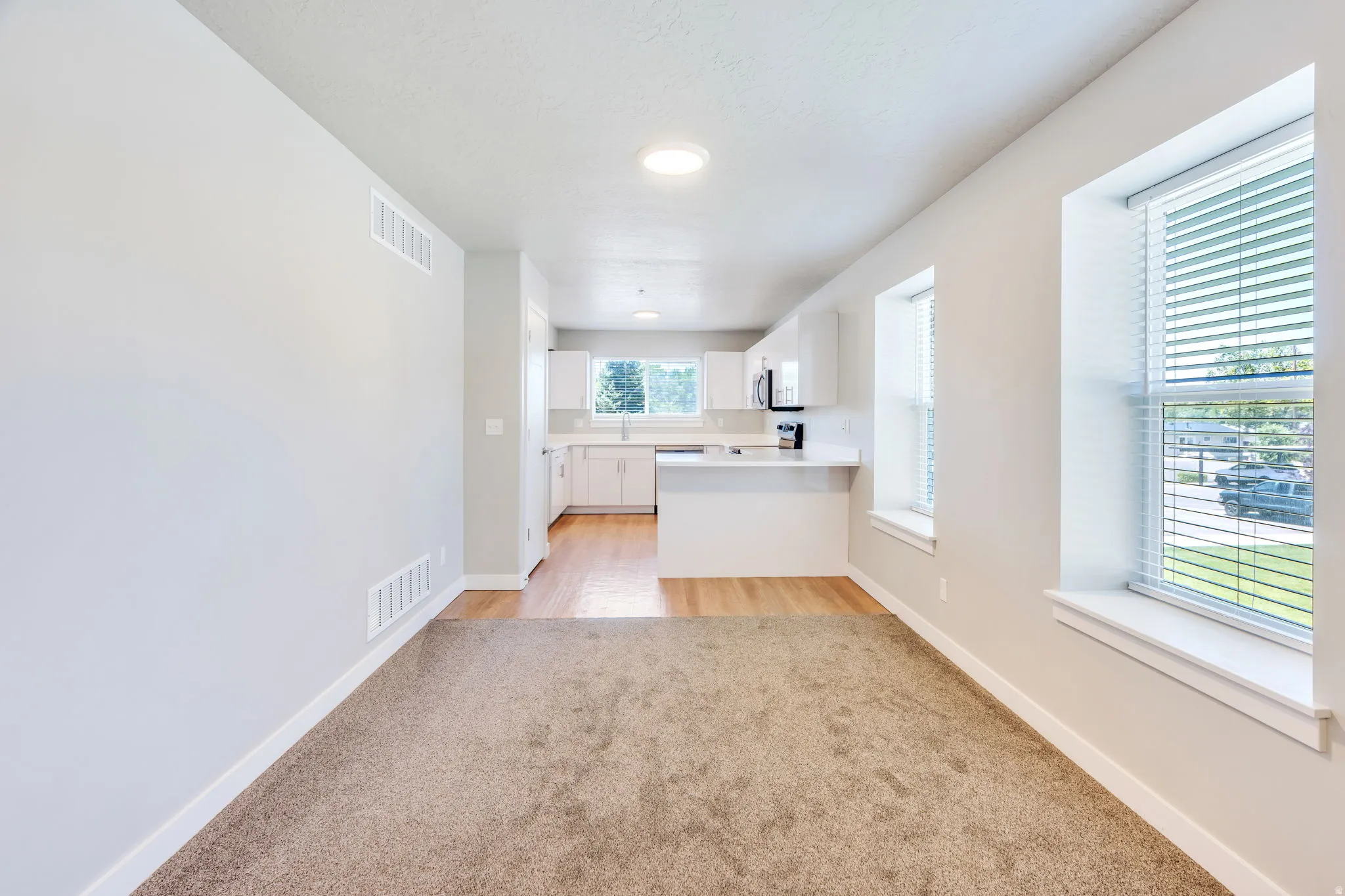 Open concept living space featuring neutral paint, recessed lighting, and an integrated kitchen with white cabinetry and a breakfast bar