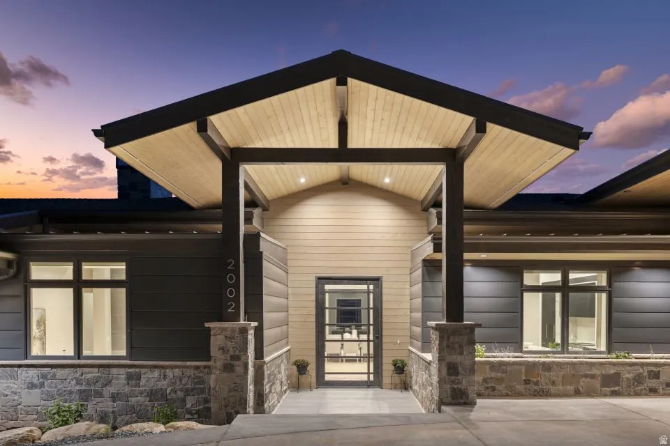 Modern architectural exterior featuring a prominent covered entryway with exposed wood-finish ceilings and recessed lighting