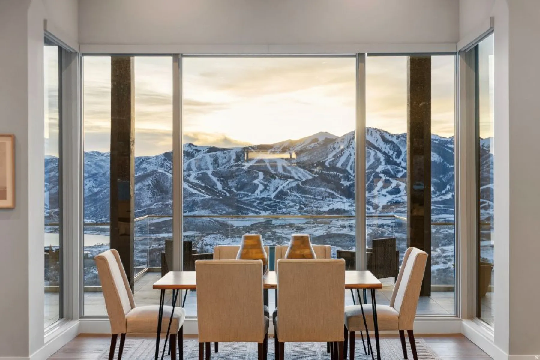 Floor-to-ceiling windows framing mountain and distant water scenery