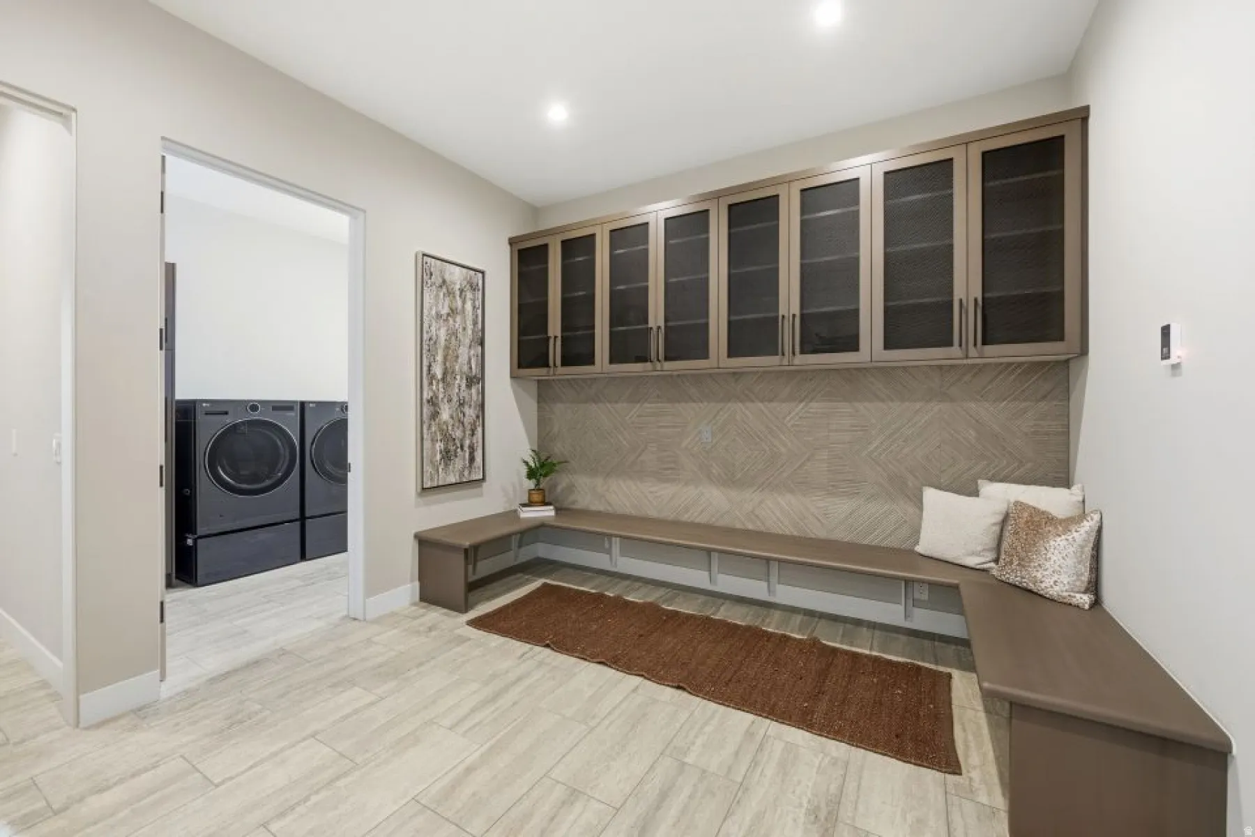 Integrated mudroom with built-in bench seating and overhead cabinetry featuring reeded glass inserts