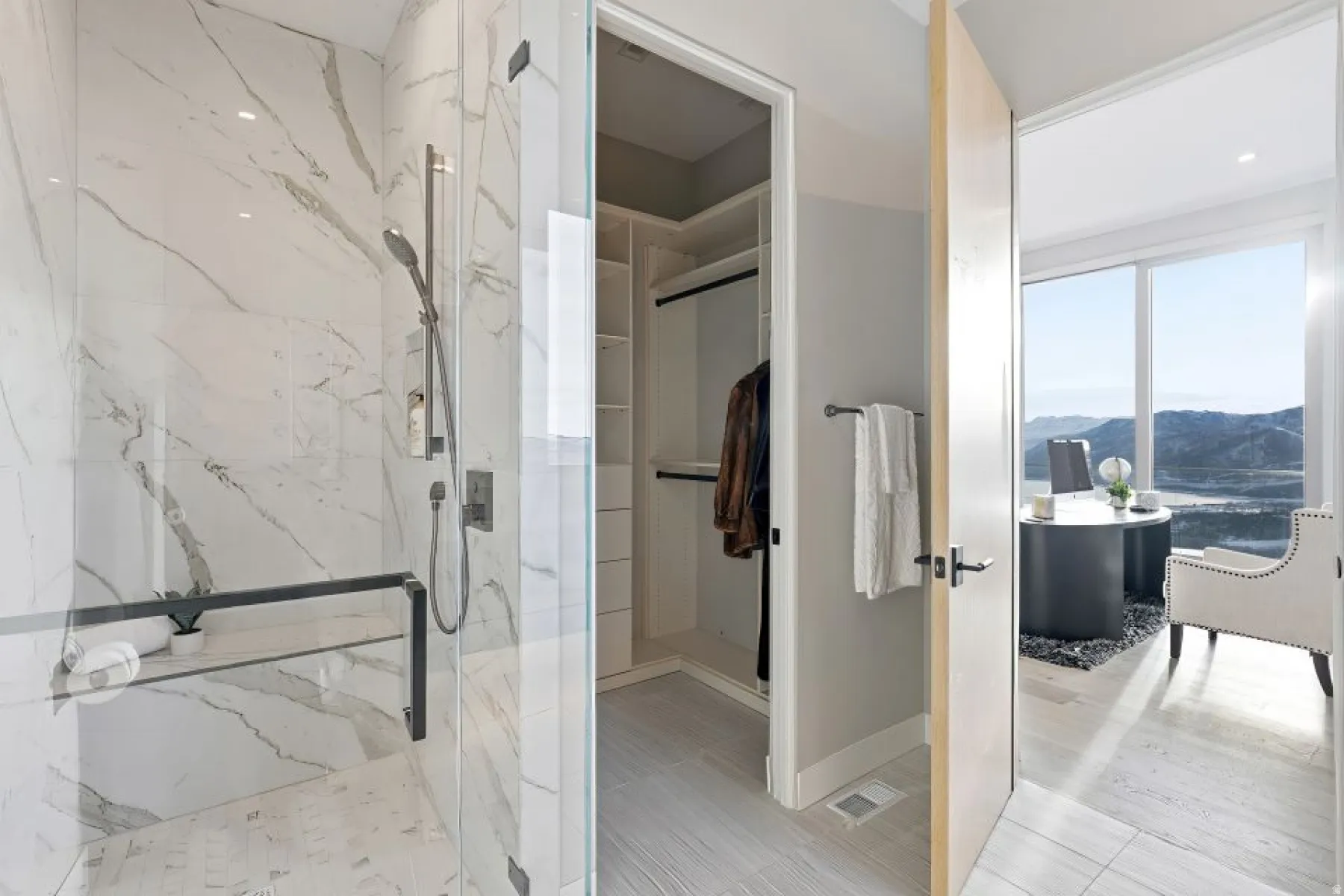Glass-enclosed shower with marble-finish tile walls and a built-in shelf