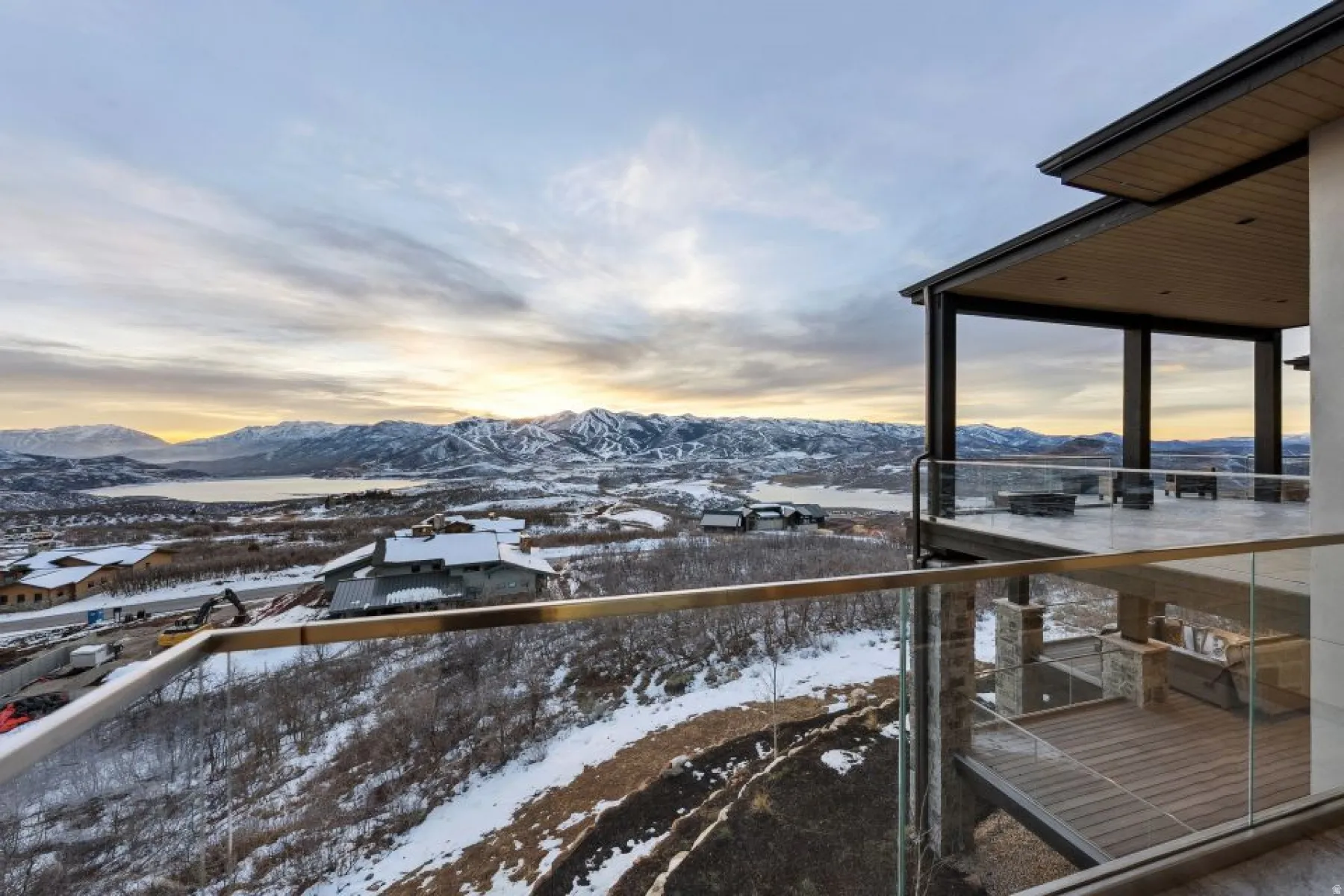Expansive outdoor terrace featuring a glass railing system and a covered patio with a wood-finish ceiling