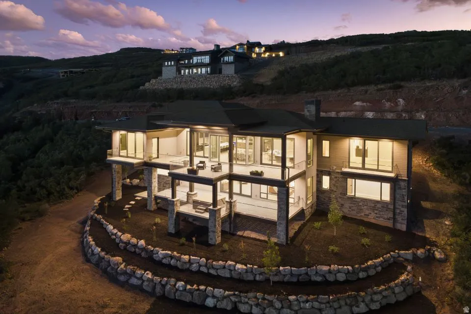 Contemporary multi-level residence featuring expansive decks, stone veneer accents, large format windows, and tiered rock landscaping