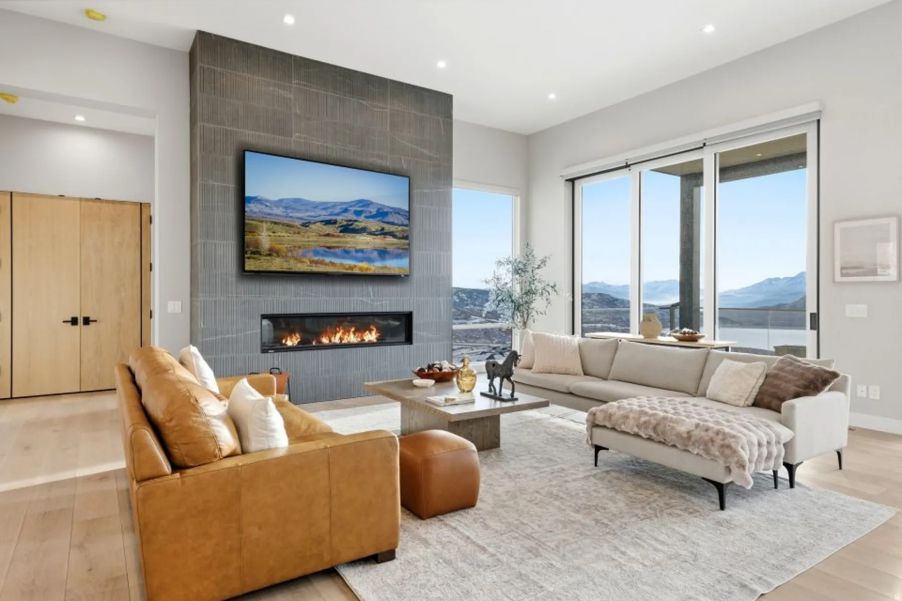 Expansive living area with a stone-look fireplace surround, linear gas fireplace, and large sliding glass doors