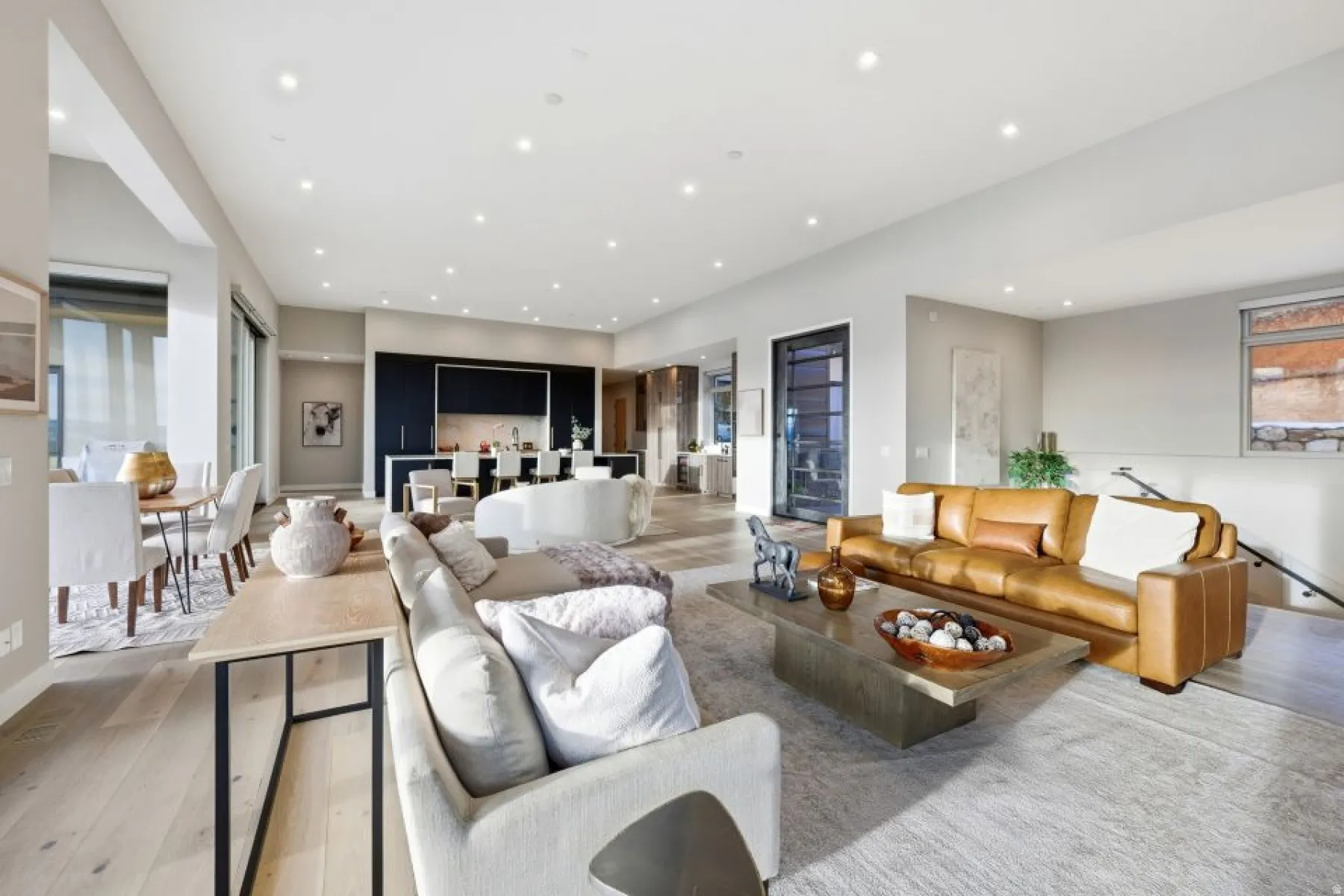 Open-concept living space featuring wood-finish flooring, recessed lighting, and a modern kitchen with dark cabinetry and a central island