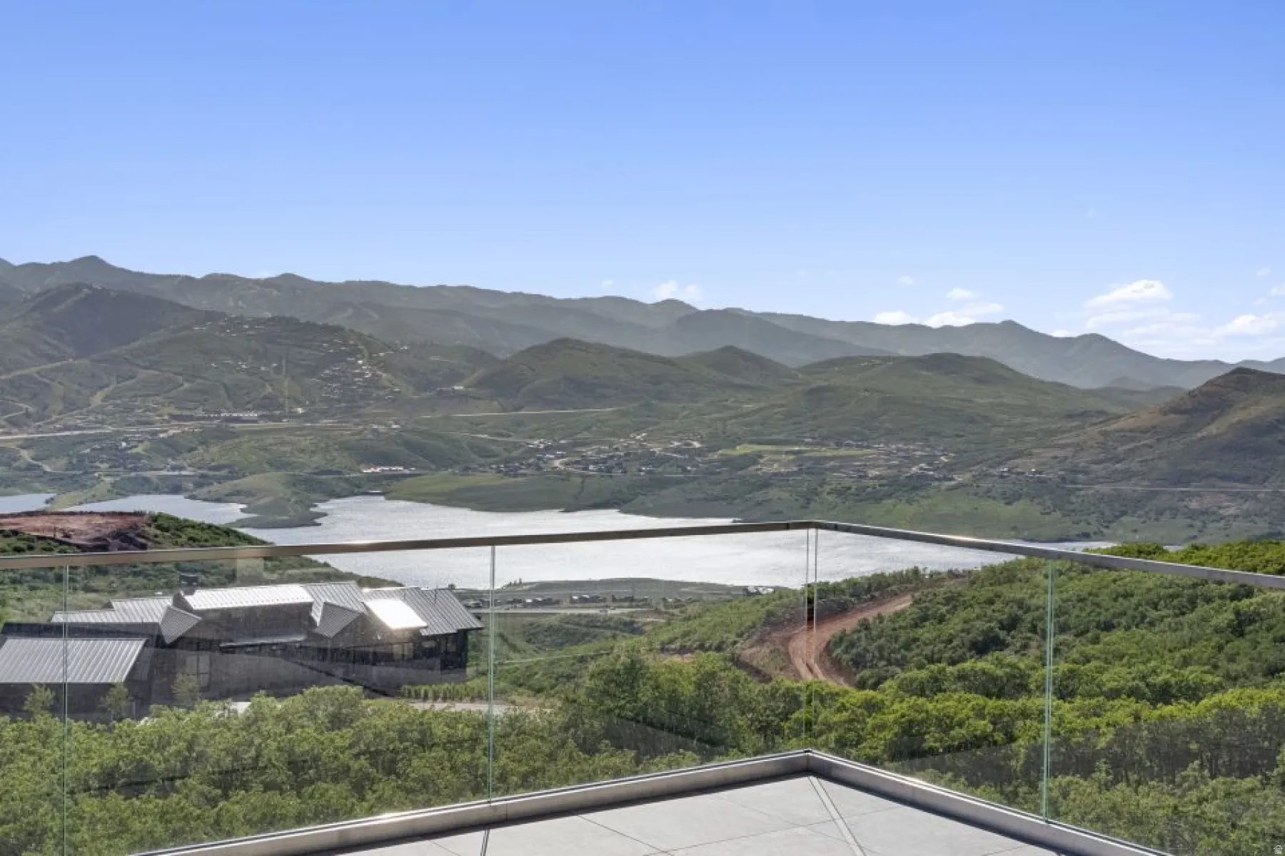 Expansive mountain and lake scenery with a contemporary glass railing