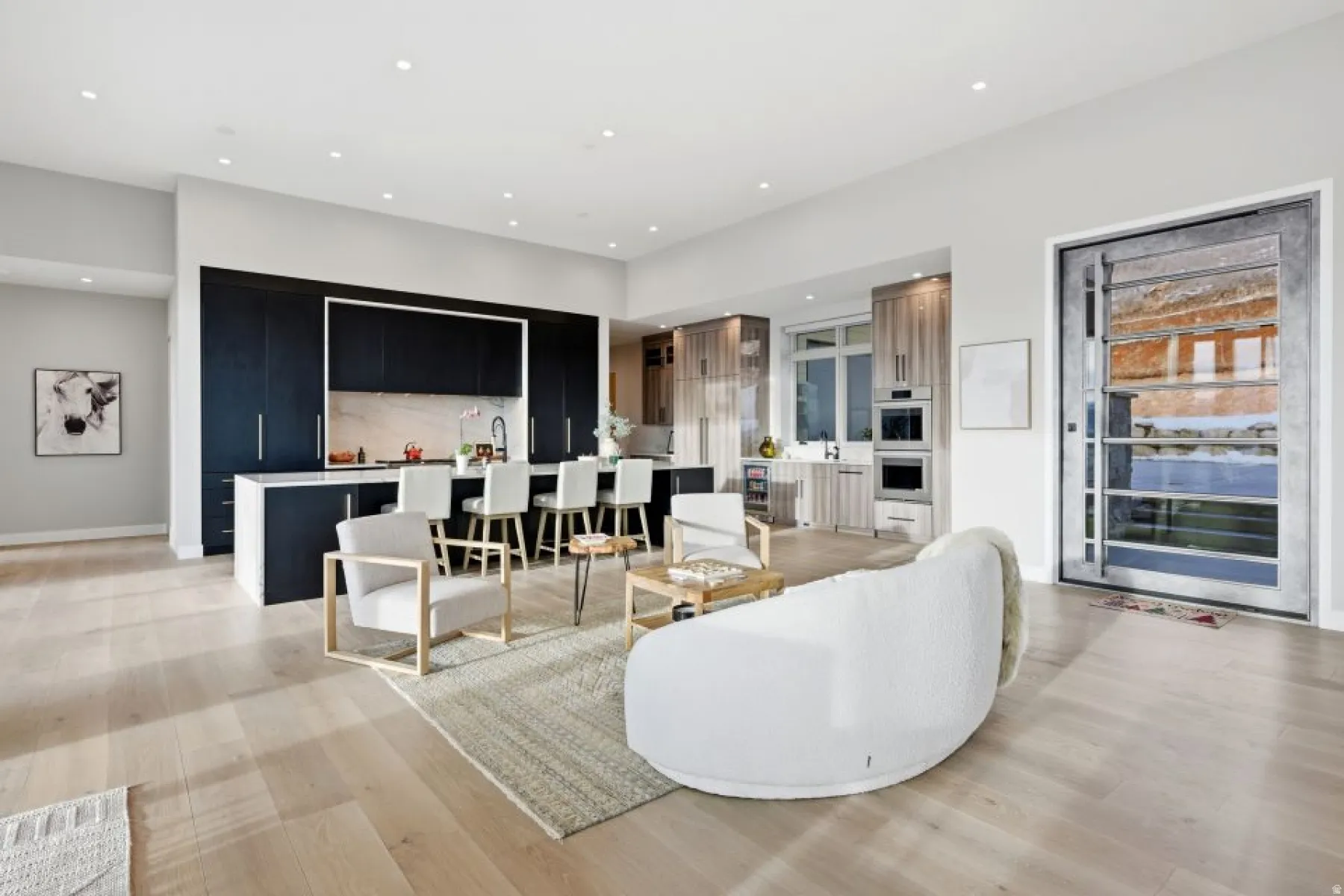 Open-concept living area with light wood-finish flooring, recessed lighting, and a modern kitchen