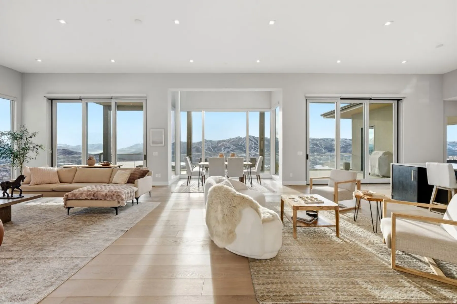 Spacious open-concept living area featuring light wood-finish flooring, recessed lighting, and expansive sliding glass doors