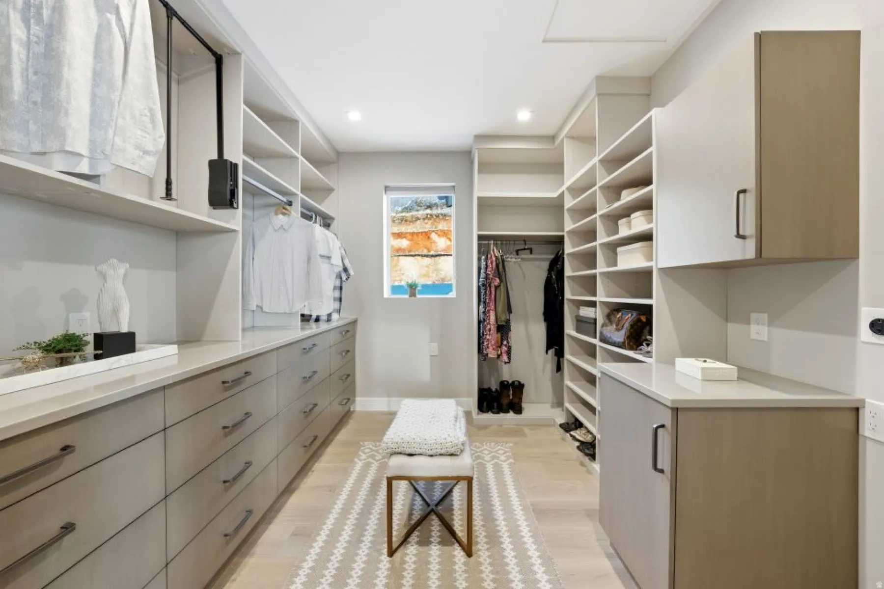 Expansive custom closet featuring extensive built-in cabinetry and shelving, a window providing natural light, recessed lighting, and light wood-finish flooring