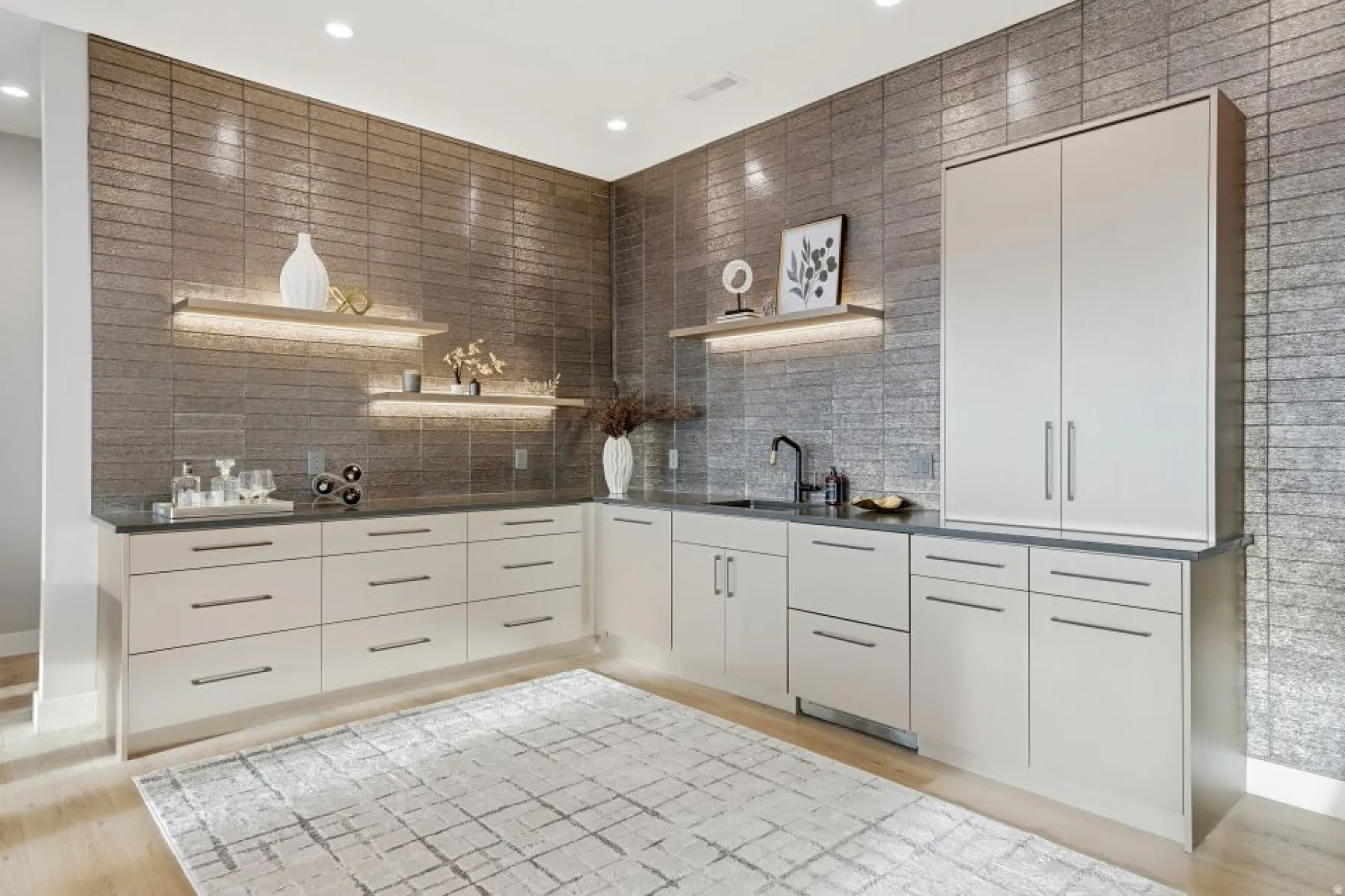 Custom bar area featuring extensive cabinetry, dark countertops, and a full-height textured wall