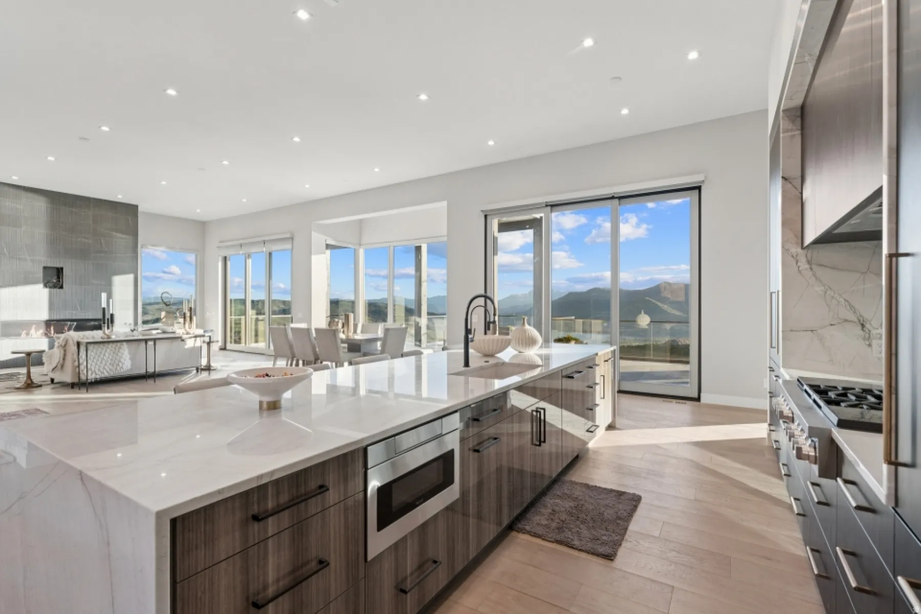 Spacious kitchen featuring a large waterfall island with integrated microwave, wood-finish cabinetry, and a black faucet