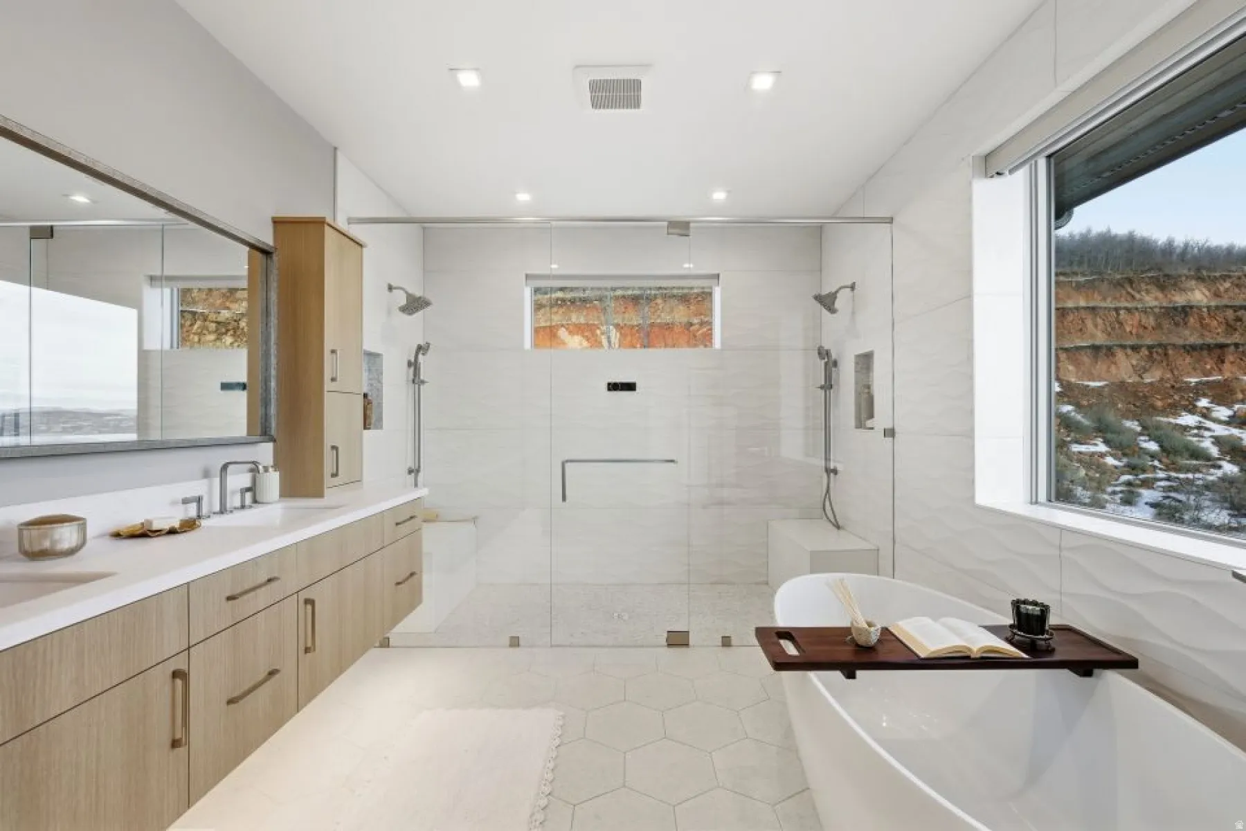 Spacious bathroom featuring a dual vanity with light wood-finish cabinetry and white countertops