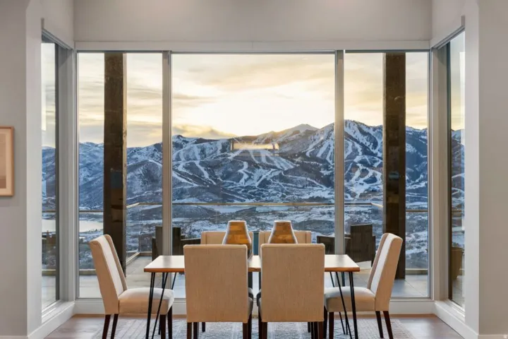 Floor-to-ceiling windows framing mountain and distant water scenery