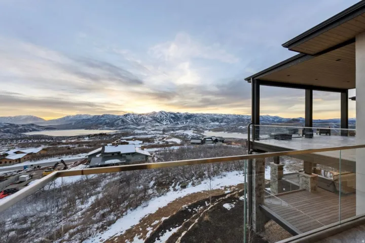 Expansive outdoor terrace featuring a glass railing system and a covered patio with a wood-finish ceiling