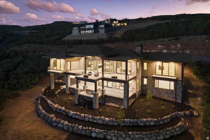 Contemporary multi-level residence featuring expansive decks, stone veneer accents, large format windows, and tiered rock landscaping