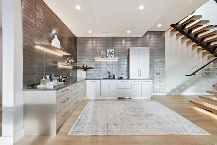 Contemporary wet bar area featuring a textured metallic-finish accent wall, white cabinetry, integrated sink, and recessed lighting