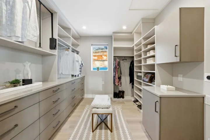 Expansive custom closet featuring extensive built-in cabinetry and shelving, a window providing natural light, recessed lighting, and light wood-finish flooring