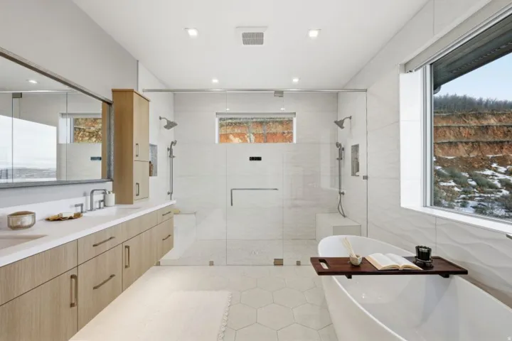 Spacious bathroom featuring a dual vanity with light wood-finish cabinetry and white countertops