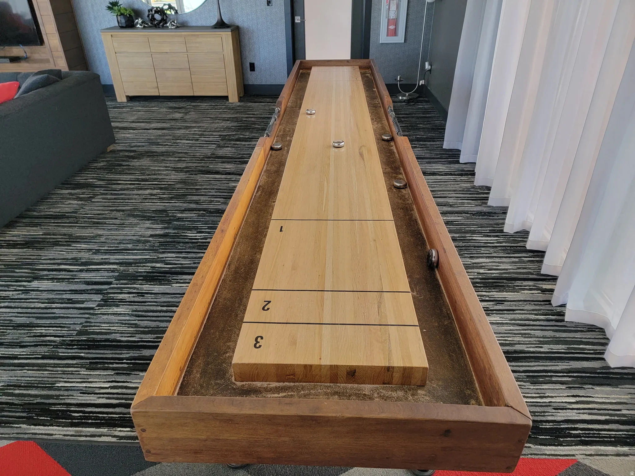Shuffleboard table featuring a light wood playing surface and dark wood trim