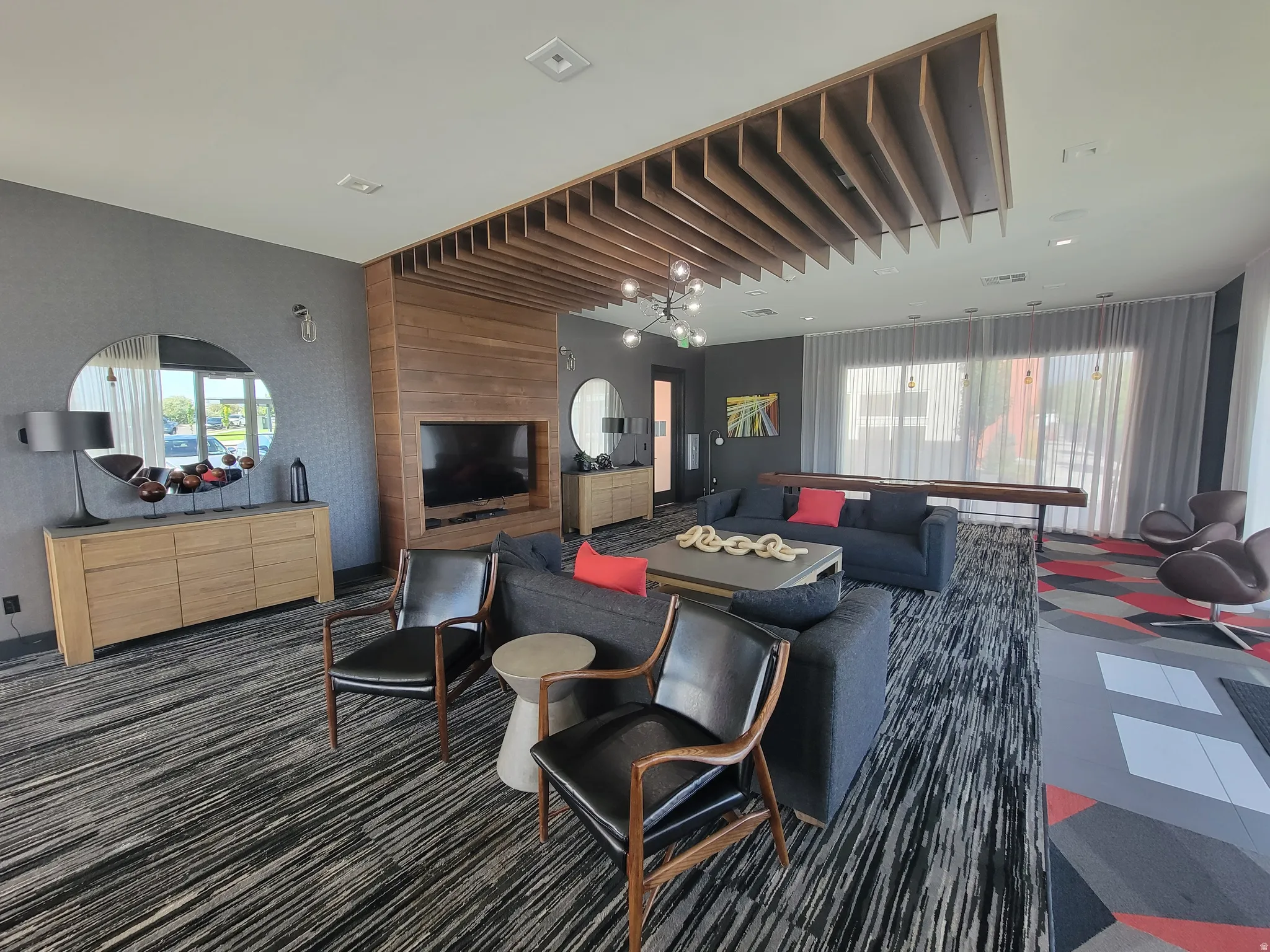 Spacious interior featuring a wood-slat ceiling accent, full-height window treatments, and patterned carpeting