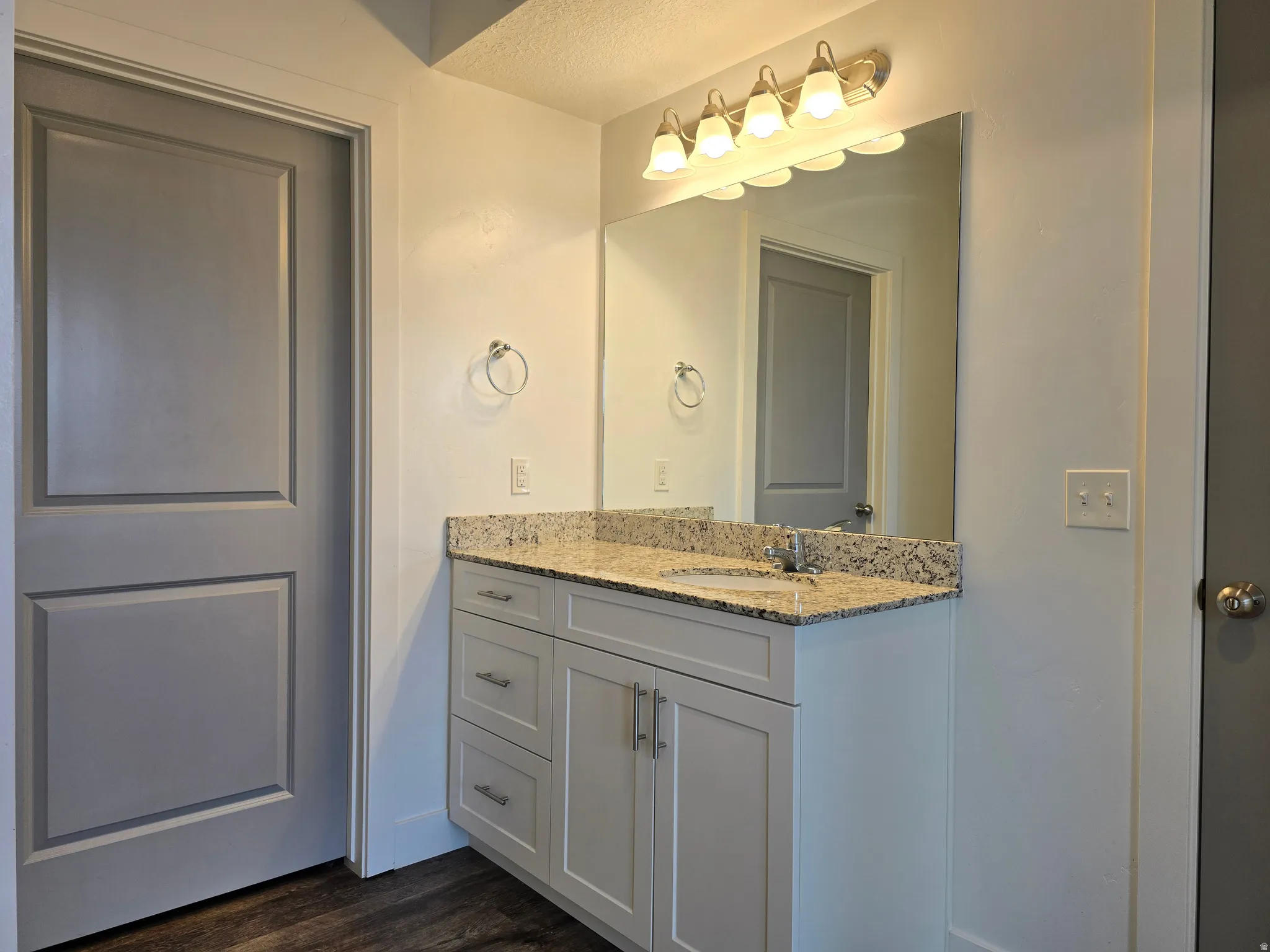 Bathroom vanity featuring a light granite countertop, undermount sink, and brushed nickel hardware
