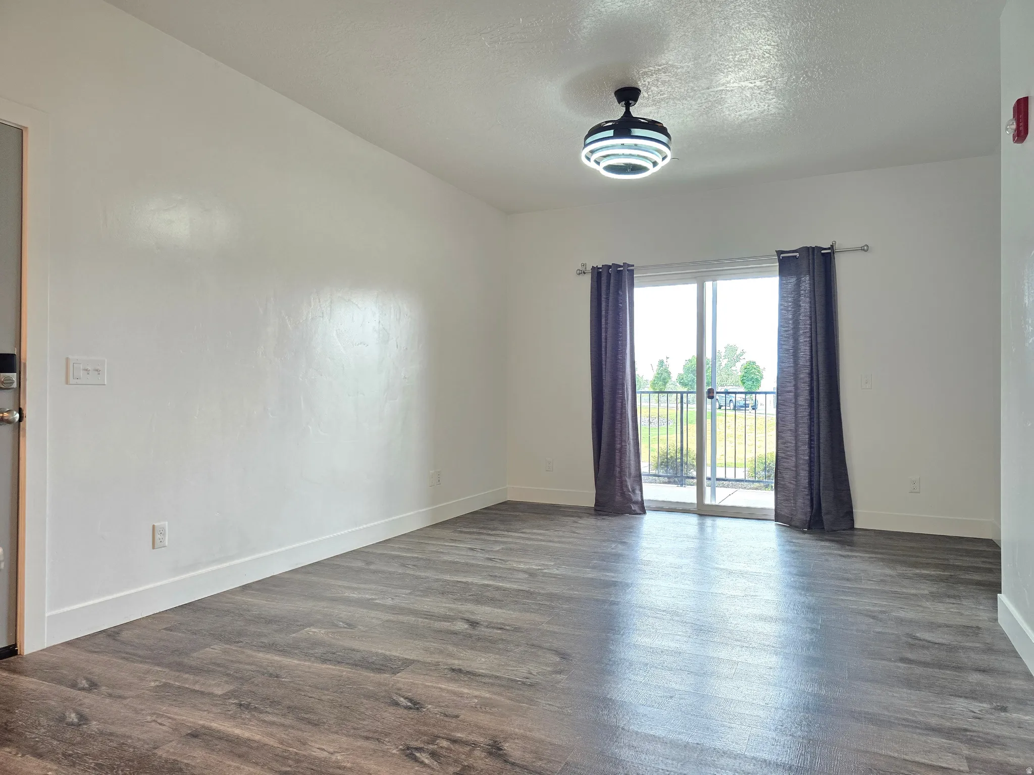Expansive room featuring wood-finish flooring, crisp white walls, and a contemporary ceiling light fixture