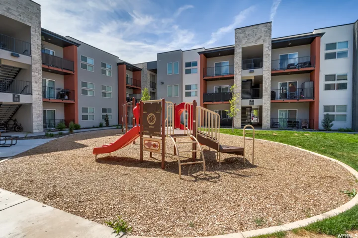 Community playground area with wood chip surfacing, green lawn border, and a concrete pathway