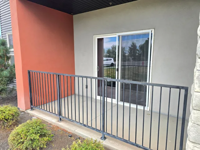 Private patio area with concrete flooring, a black metal railing, and direct slider access