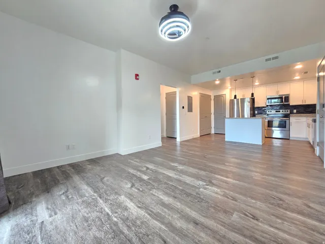 Open-concept living space featuring wood-finish flooring, white walls, and a contemporary ceiling fixture