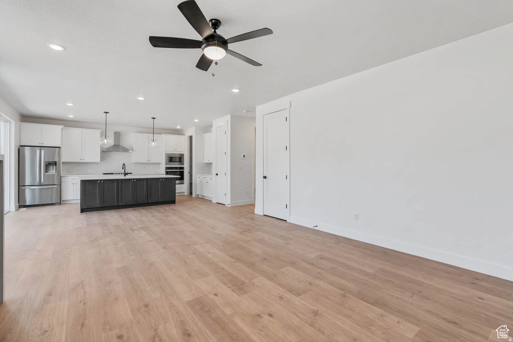 Open-concept living area featuring light wood-finish flooring, recessed lighting, and a contemporary ceiling fan