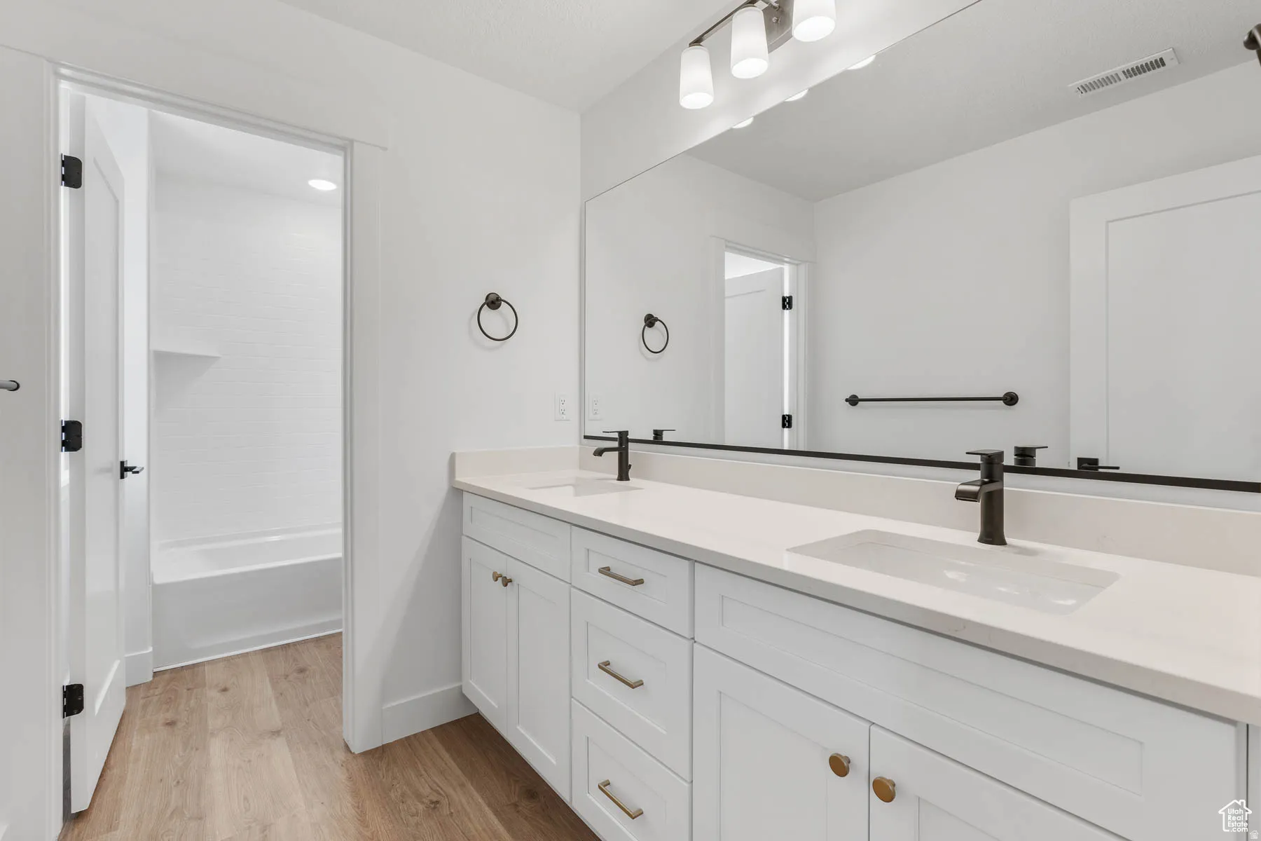 Double vanity with white cabinetry, gold-tone hardware, and integrated rectangular sinks