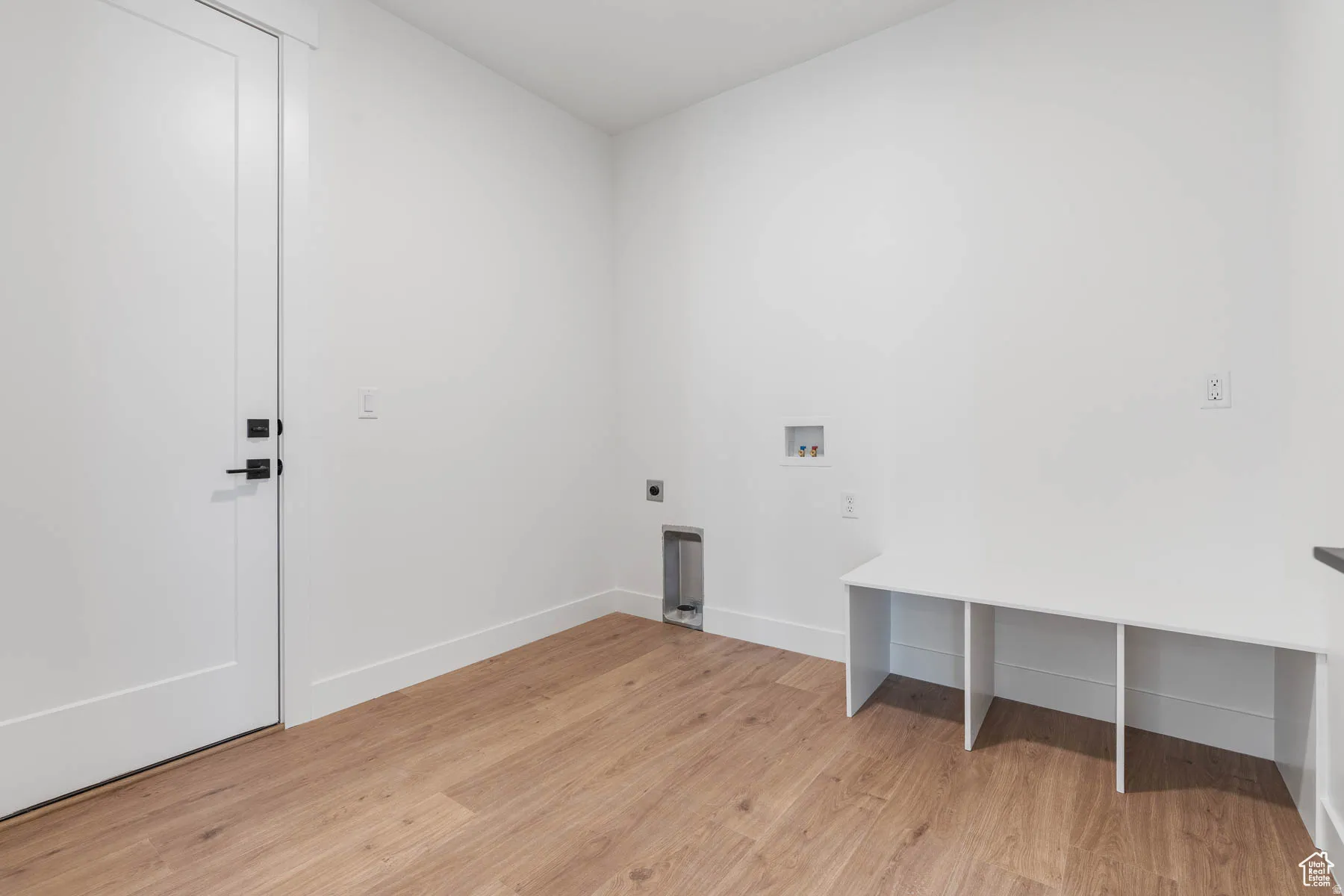 Utility room with wood-finish flooring, white walls, and a built-in white bench