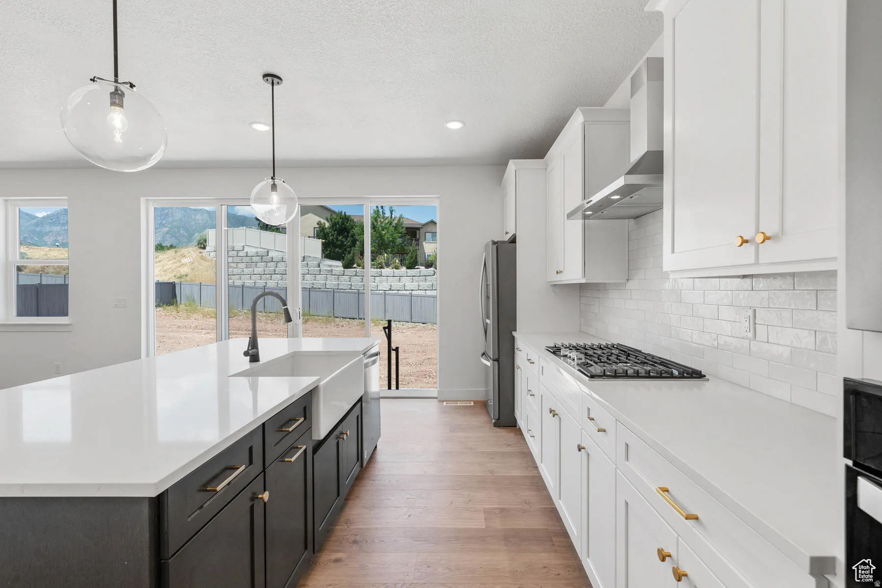 Kitchen featuring a large island with a farmhouse sink, stone countertops, and wood-finish flooring