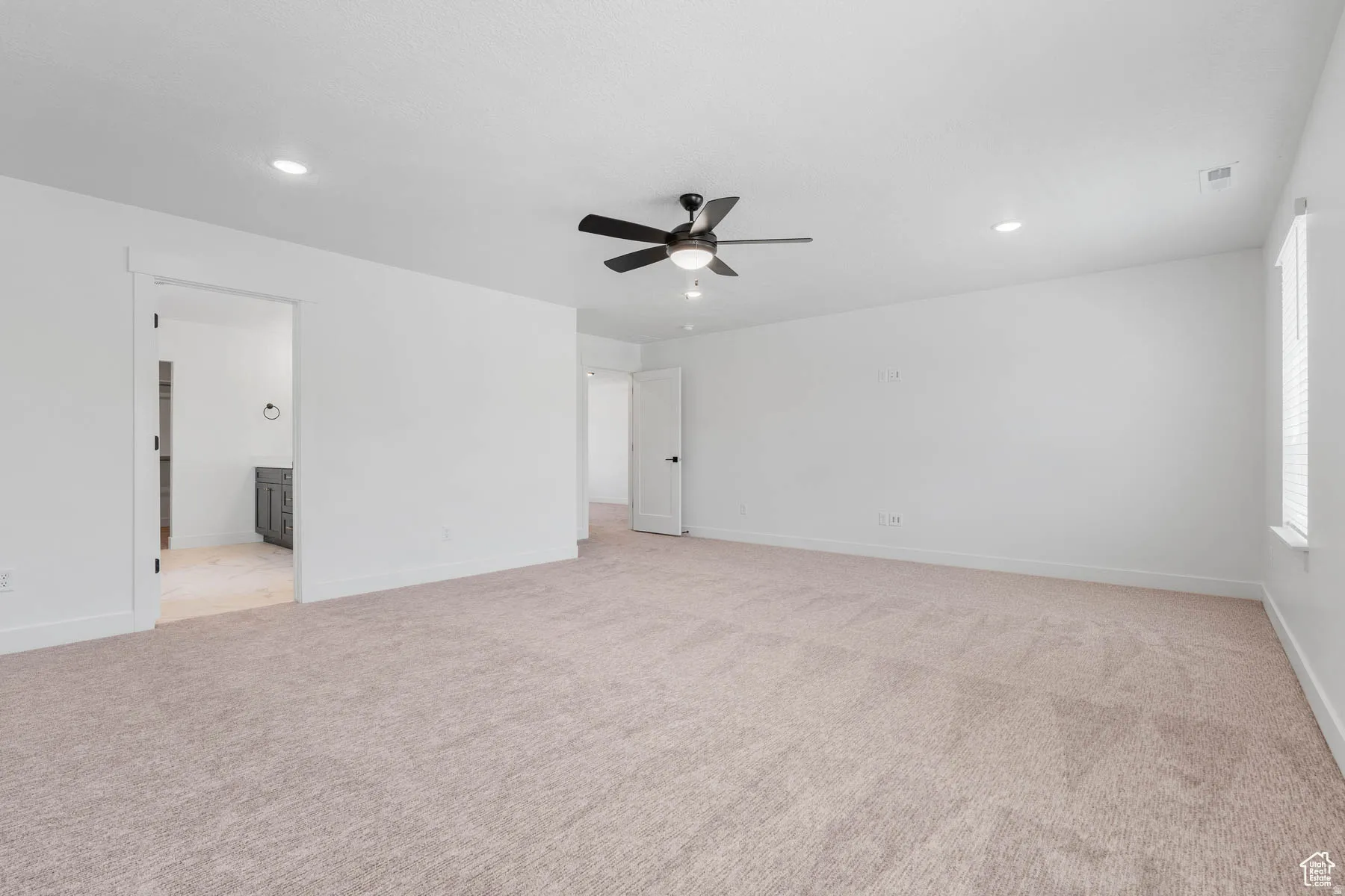 Spacious room featuring neutral carpet, white walls, recessed lighting, and a ceiling fan