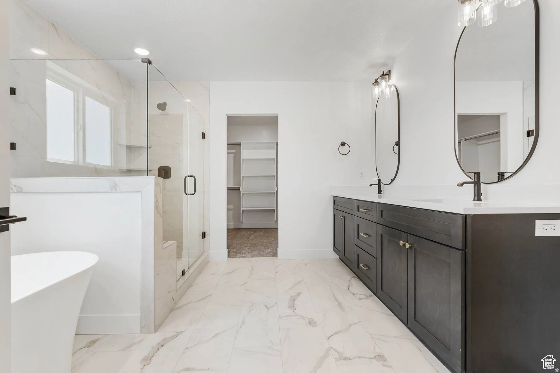 Spacious bathroom featuring a dual vanity with dark wood-finish cabinetry, white countertops, and matte black fixtures