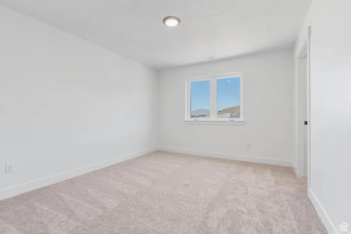 Neutral wall finishes featuring a window with a mountain backdrop, complemented by light-toned carpeting and white baseboards