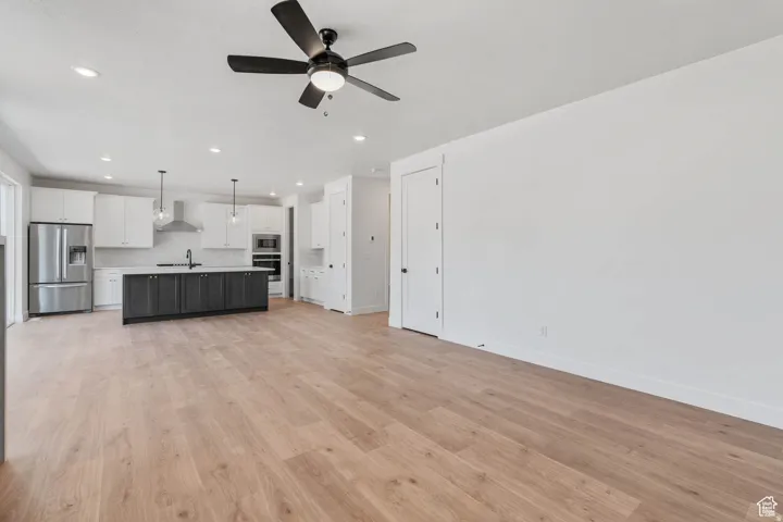 Open-concept living area featuring light wood-finish flooring, recessed lighting, and a contemporary ceiling fan