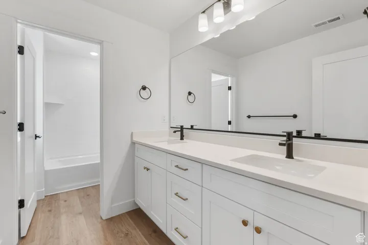 Double vanity with white cabinetry, gold-tone hardware, and integrated rectangular sinks