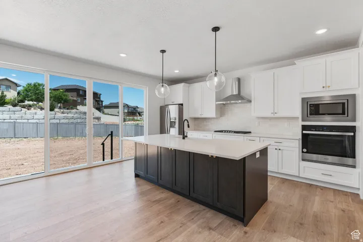 Modern kitchen featuring a dark-toned island with a light countertop, white cabinetry, and stainless steel appliances