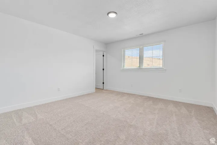 Bright room featuring light-colored carpet flooring, white walls, and a window with blinds