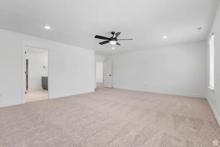 Spacious room featuring neutral carpet, white walls, recessed lighting, and a ceiling fan