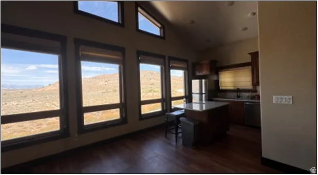 Open-concept living space featuring wood-finish flooring, a wall of windows with transom accents, and a contemporary kitchen