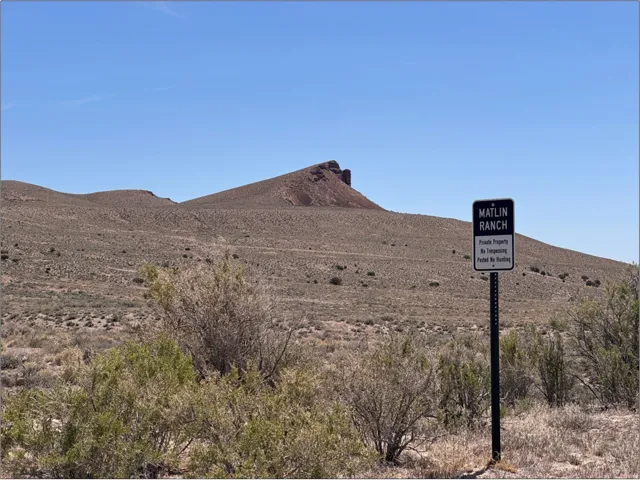 Matlin Ranch signage on a black post, set against a backdrop of arid hills and sparse vegetation