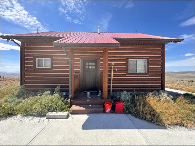 Log cabin exterior featuring a red corrugated metal roof and dark wood siding