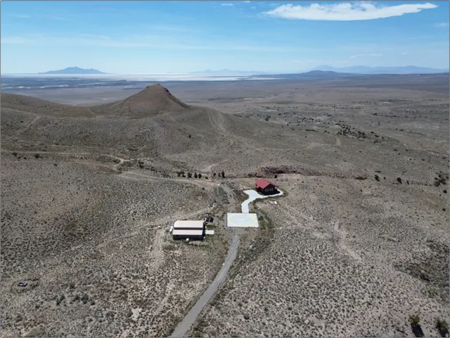 Expansive desert landscape featuring two structures with red and tan roofs, situated on a large parcel of land