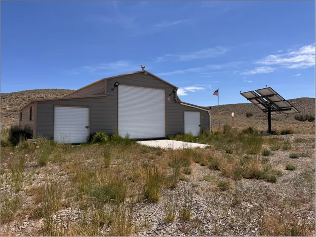 Metal building featuring a large white roll-up door, two smaller white roll-up doors, and a metal roof