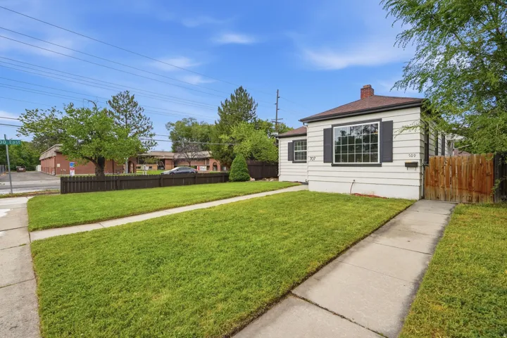 White horizontal siding exterior with dark window shutters, a front entry walkway, and a landscaped lawn