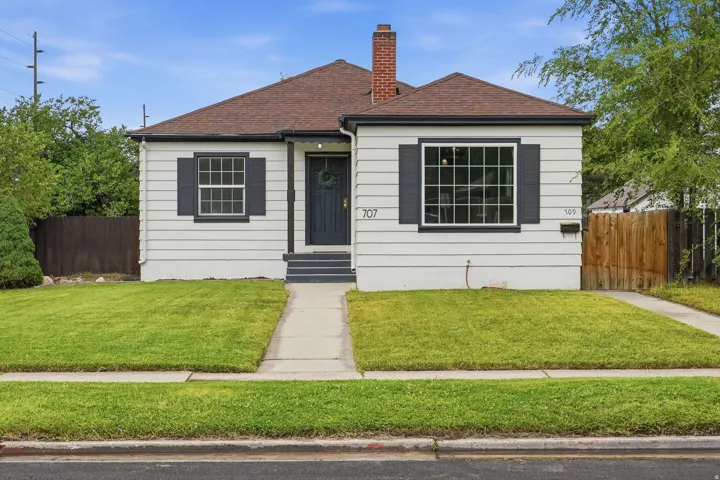 Charming single-story residence featuring a white horizontal siding exterior with dark grey trim, dark grey shutters, and a dark grey front door